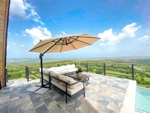 Relax on the furnished outdoor terrace with a scenic view of the lush landscape.
