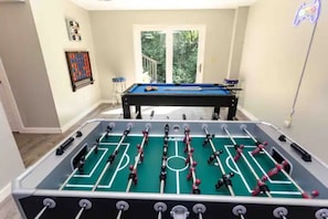 Una mesa de fútbolín en una habitación con una puerta que da a un balcón.