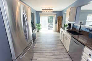 Une cuisine moderne dotée d’appareils électroménagers en acier inoxydable, de planchers en bois clair et offrant une vue sur l’extérieur.