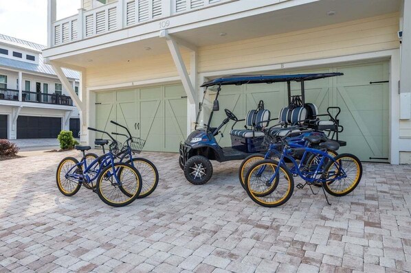 A residential garage with a golf cart and two bicycles parked outside.