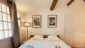 Et hotelværelse med en stor seng, to puder, et natbord, en lampe og to billeder i rammer på væggen.