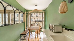 A narrow kitchen with a dining area, a view of buildings, a hanging light fixture, and a built-in microwave.