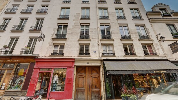 A multi-story building with a row of shops on the ground floor, including a clothing store and a boutique. - 2 bedroom in the heart of Le Marais! (Paris)