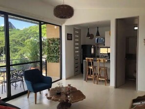 Relax in this spacious living area with a sliding door leading to an outdoor space, a dining table, and a fully equipped kitchen.