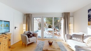 A living room with a sofa, armchair, and a television on a wooden cabinet.