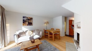 Un salon avec un canapé, une table basse et une table à manger. Il y a un tableau au mur et une lampe.