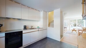 A modern kitchen with white cabinets, a black oven, and a coffee maker on the counter.