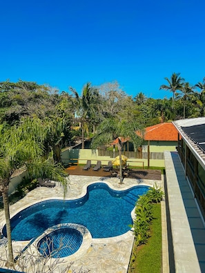 A swimming pool with a wavy edge, surrounded by palm trees and lounge chairs. - Pousada BeachCamp Maresias (São Sebastião)