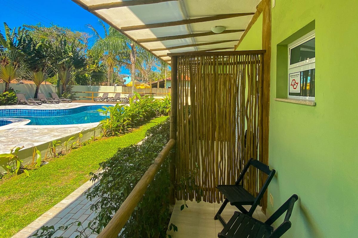 A balcony with a view of a swimming pool, a wooden fence, and a green wall.