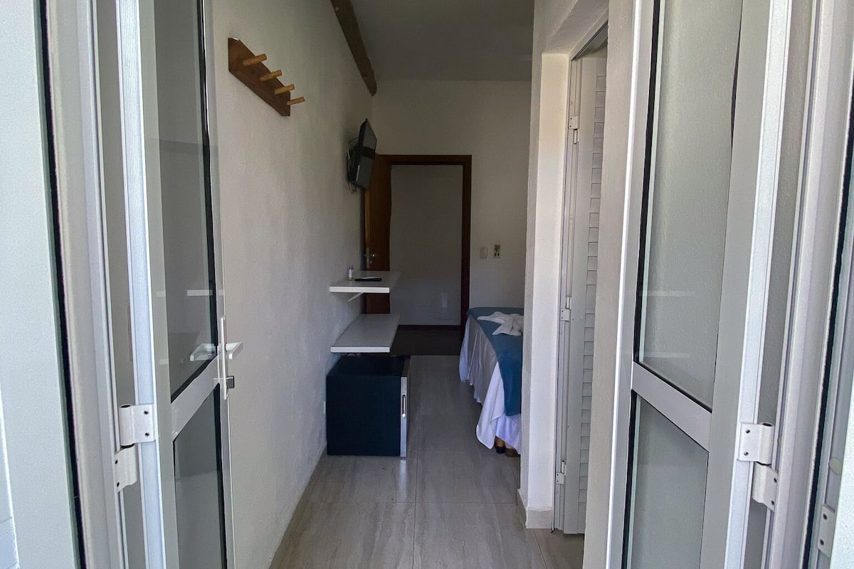 A narrow hallway with a bed, a small table, and a cabinet.