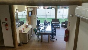 A room with a desk, chairs, a fire extinguisher, and a view of the outside. - Pousada BeachCamp Maresias (São Sebastião)