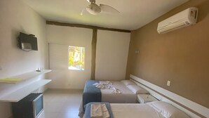 A hotel room with two single beds, a ceiling fan, an air conditioner, a window with blinds, a small TV on a shelf, and a trash bin. - Pousada BeachCamp Maresias (São Sebastião)
