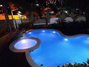 A swimming pool with a unique curved design, surrounded by a wooden deck and potted plants. - Pousada BeachCamp Maresias (São Sebastião)
