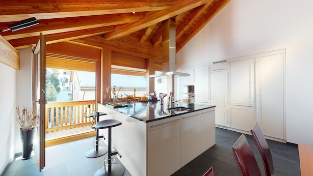 A modern kitchen with a central island, white cabinetry, and a view of the outside. - Large 3-½ room maisonette on the 2nd floor. (Silvaplana-Surlej)