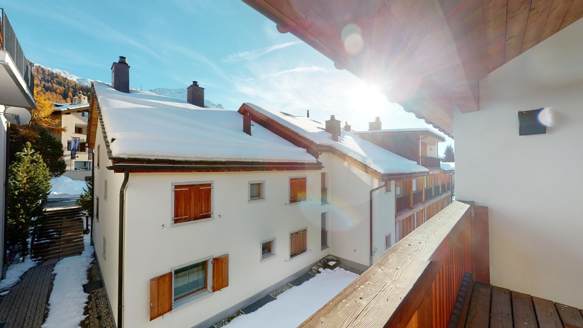 A snow-covered residential area with traditional architecture, including wooden shutters and chimneys.