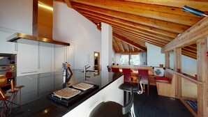 A modern kitchen with a central island, stainless steel appliances, and a wooden ceiling. - Large 3-½ room maisonette on the 2nd floor. (Silvaplana-Surlej)
