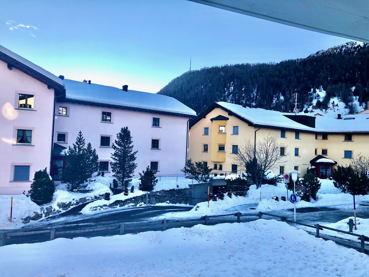 Une rangée d’immeubles à étages, aux toits couverts de neige, avec une chaîne de montagnes en arrière-plan.