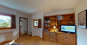 A cozy living room with a wooden TV stand, bookshelves, and a fireplace.