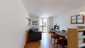 A compact living space with a sofa, dining table, chairs, a TV, and a wooden cabinet. - 2-room apartment on the 1st floor. (Celerina/Schlarigna)