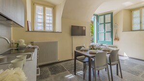 Une cuisine compacte avec un coin repas, un radiateur et un téléviseur fixé au mur.