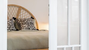 Ein Bett mit einem gewobenen Kopfteil, gemusterten Kissen und einer schlichten Bettdecke.