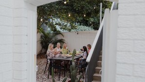 Eine Terrasse im Freien mit Tisch, gedeckt für eine Mahlzeit, umgeben von Stühlen und einer Kakteenpflanze.