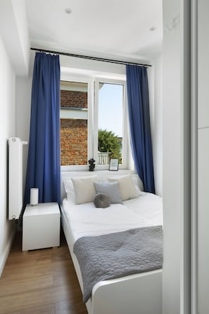Relax in this serene bedroom with a large bed, nightstand, and window offering a view of the surrounding greenery.