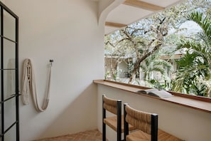 A room with a window overlooking a garden, a chair, and a wall-mounted rope.