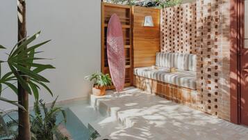Un área de piscina con un banco de madera, una tabla de surf y plantas en macetas.