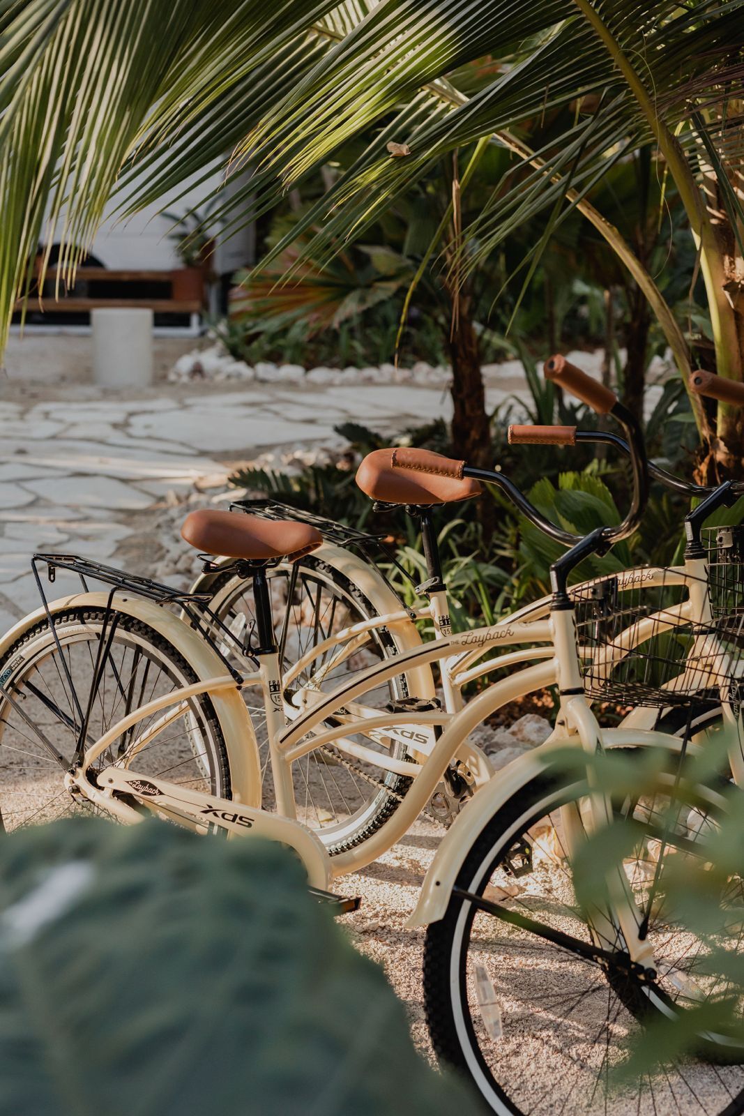 Una bicicleta tándem con una cesta y asiento marrón estacionada sobre un camino de piedra.