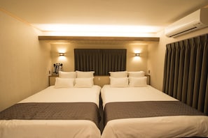 Una habitación de hotel con dos camas, una lámpara en el techo, aire acondicionado y una cortina.