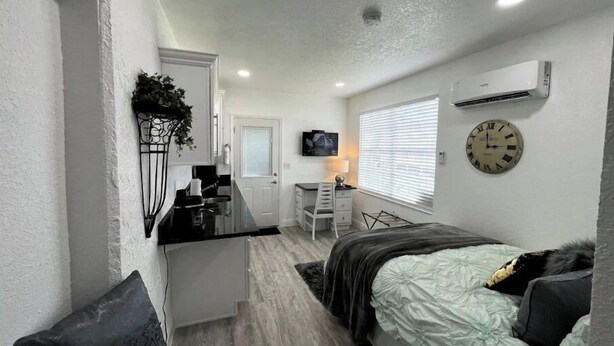 A compact bedroom with a bed, a desk, and a TV. - Modern studio apartment with covered outside seating area (Spring Hill)