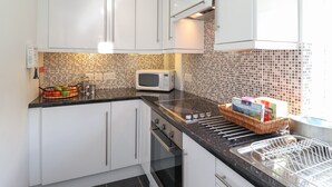 Una cocina moderna con armarios blancos, un microondas y un lavabo con escurreplatos.