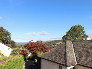 A narrow street in a hilly area with houses on either side, a clear sky, and autumn foliage. - Uplands Retreat (Windermere)