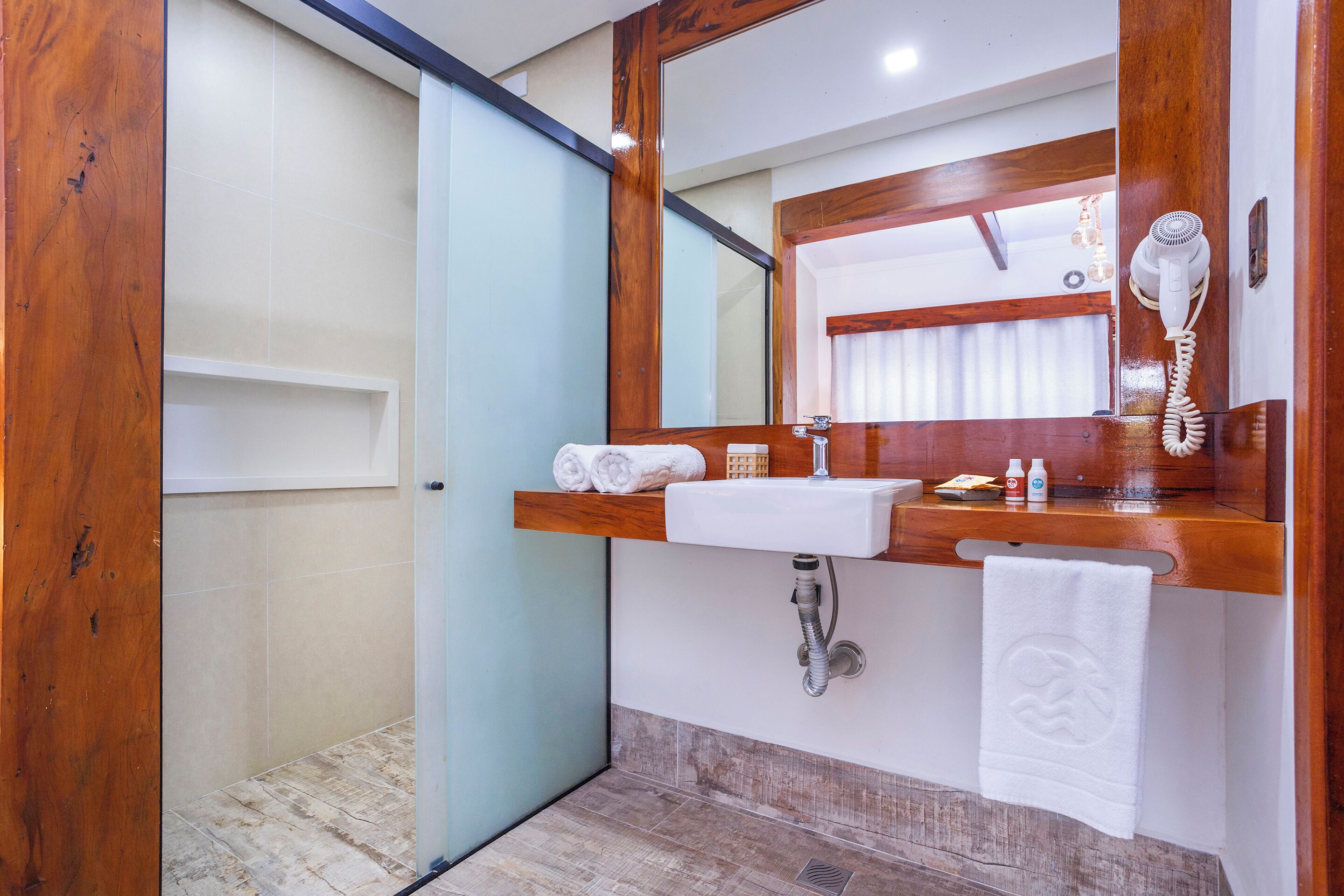 A bathroom with a wooden vanity, a mirror, a sink, a towel rack, and a hairdryer.