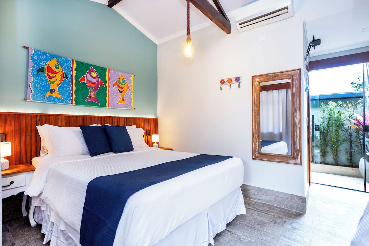 Un dormitorio ordenado con una cama grande, cabecera de madera y vistas al exterior a través de un ventanal.
