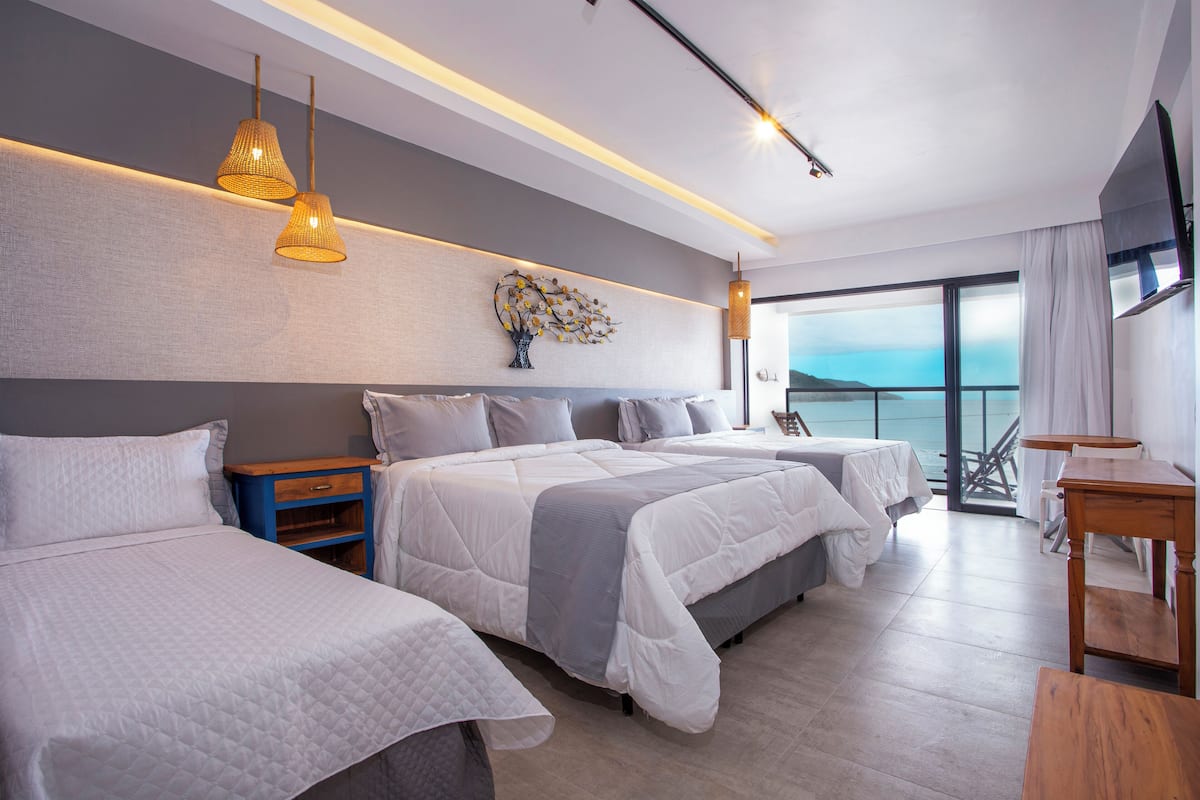Una habitación de hotel moderna con dos camas, una mesita de noche de madera, un ventanal con vistas y un balcón.