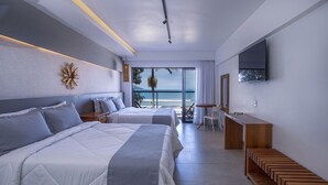Una habitación de hotel moderna con dos camas, un escritorio y un ventanal con vistas al mar.