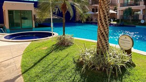 Une piscine entourée de palmiers et un bâtiment doté de balcons.