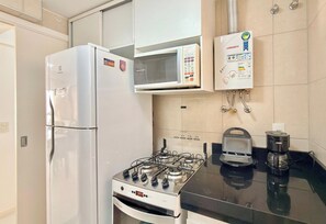 Une cuisine équipée d’un réfrigérateur blanc, d’un four à micro-ondes, d’une cuisinière à gaz et d’une machine à café.