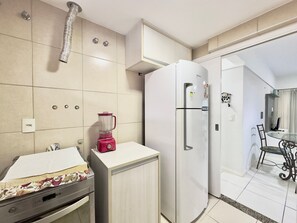 A compact kitchen with a refrigerator, a blender, a microwave, and a small dining area with a table and chairs.