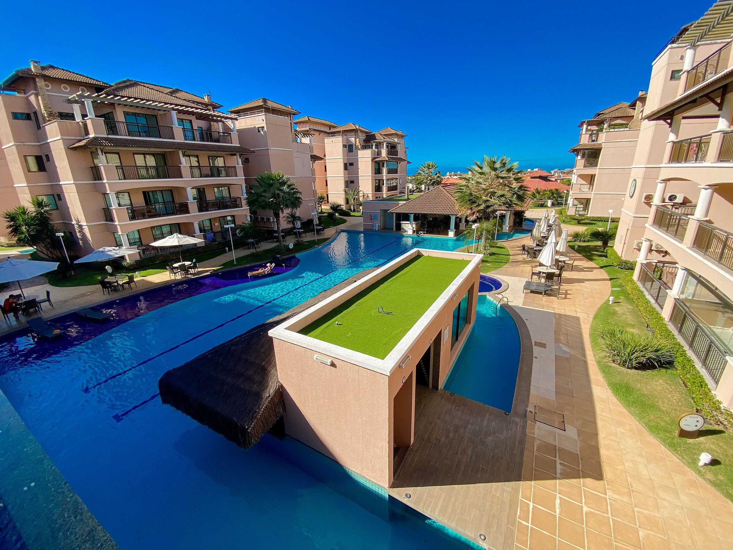 A hotel with multiple swimming pools, a tennis court, and a well-maintained garden.
