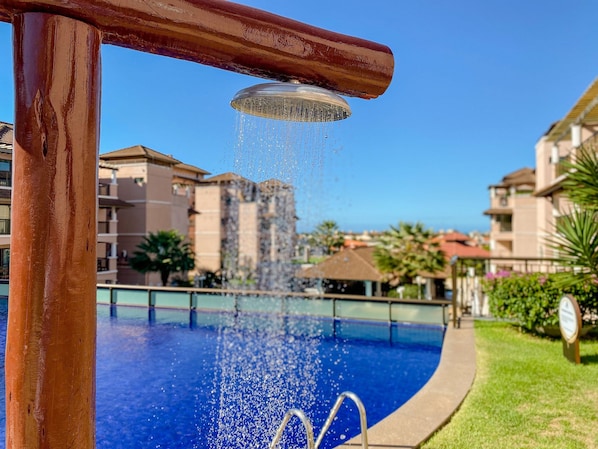 A swimming pool with a water fountain, surrounded by buildings. - Beverly Hills no Porto das Dunas (Aquiraz)