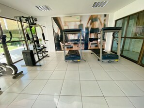 Une salle de sport équipée de machines de cardio, de matériel de musculation et d’un grand miroir.