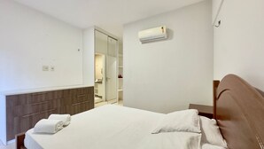 Une chambre d’hôtel équipée d’un lit, d’une armoire, d’un miroir et d’un appareil de climatisation.