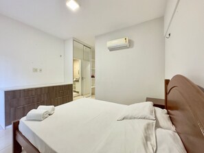 Habitación de hotel con cama, armario, espejo y aire acondicionado.