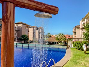 A swimming pool with a water fountain, surrounded by buildings.