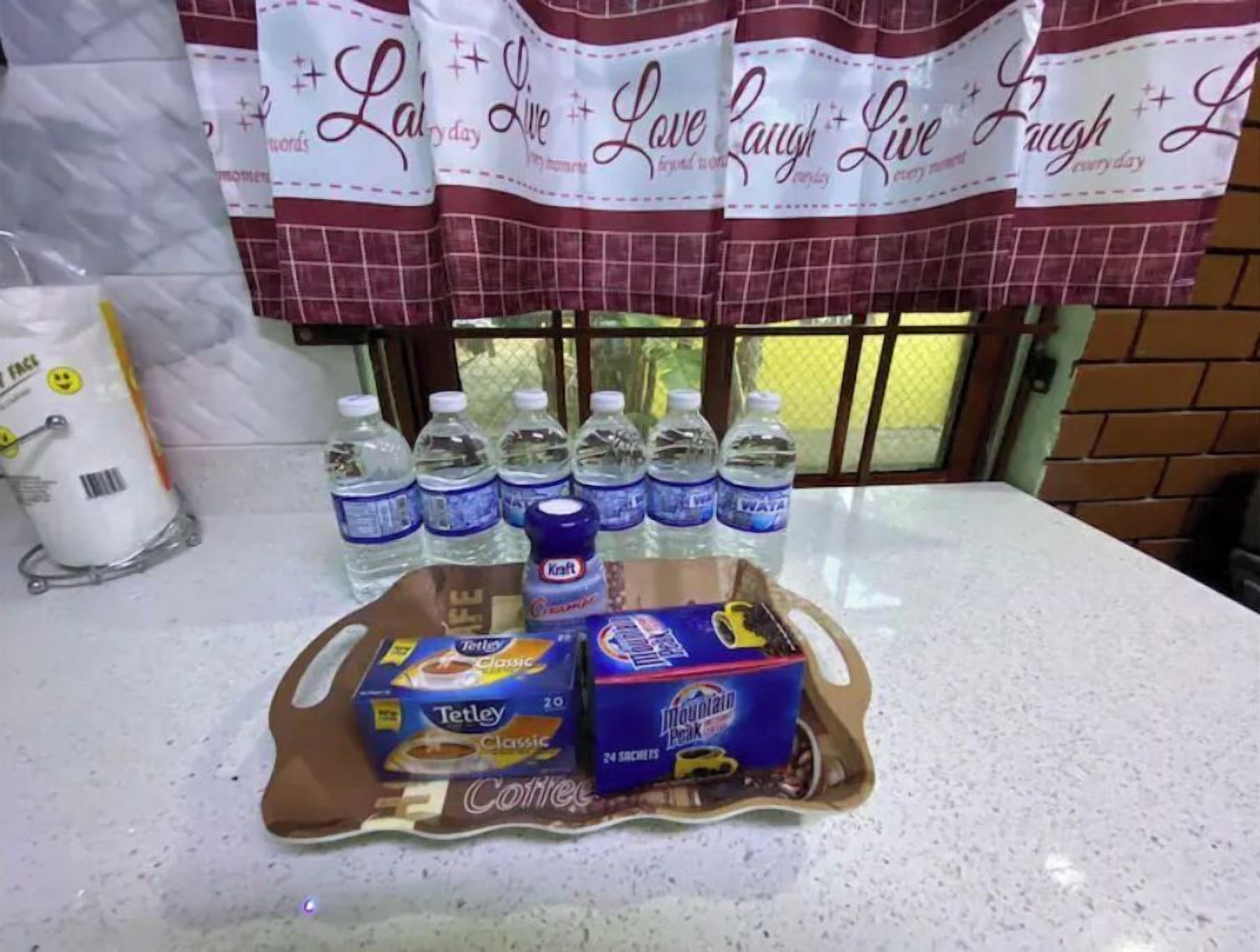 A kitchen counter with a water dispenser, bottles of water, coffee creamer, and coffee pods.