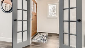 Un couloir avec une porte en bois, une fenêtre et un tapis.