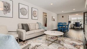 Un salon moderne avec un canapé, une table basse et un coin repas avec des chaises bleues.
